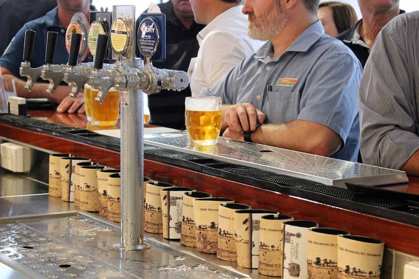 A group of people gather at a bar waiting for drinks.