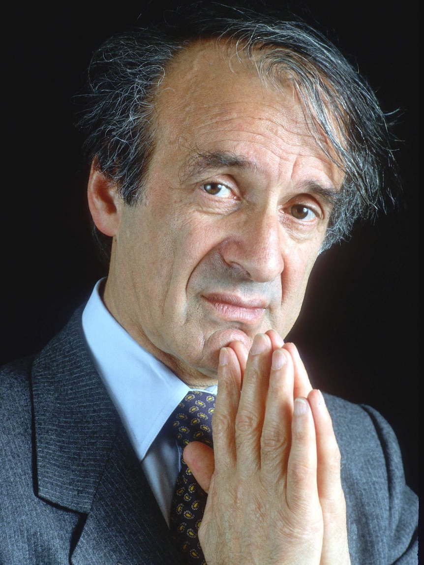 Elie Wiesel holds his hands together at his chin.
