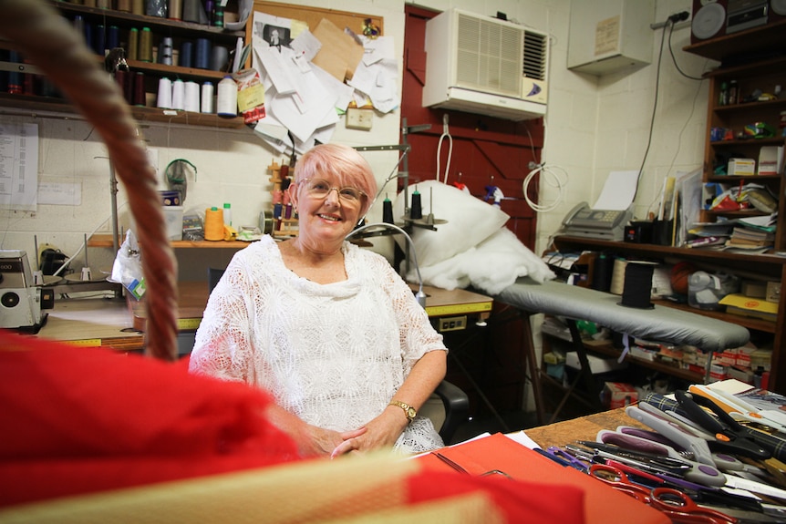 A woman smiles whilst sitting in her studio