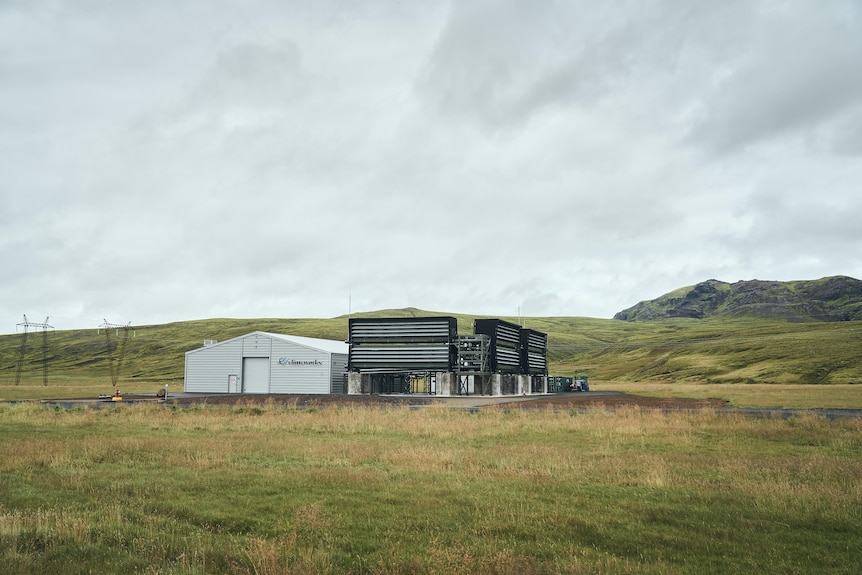 An industrial facility with sheds and metal boxes in a green field