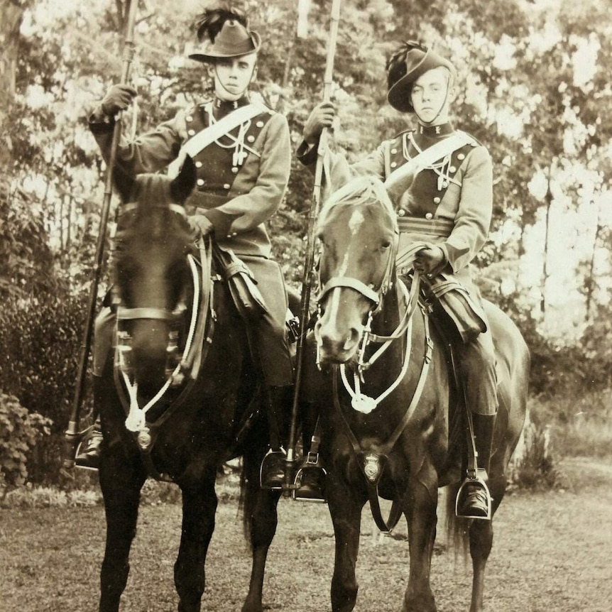 Sepia photo of two young men on horseback.