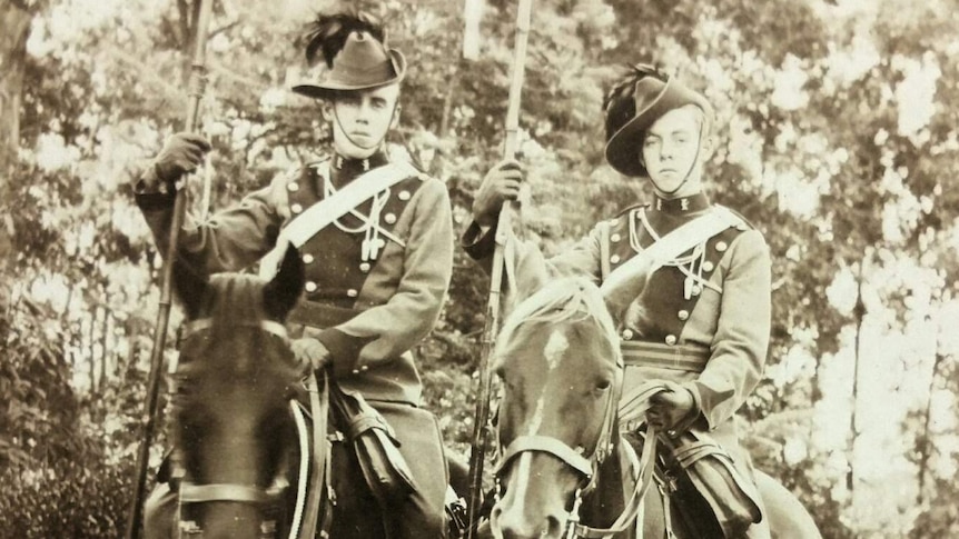 Sepia photo of two young men on horseback.