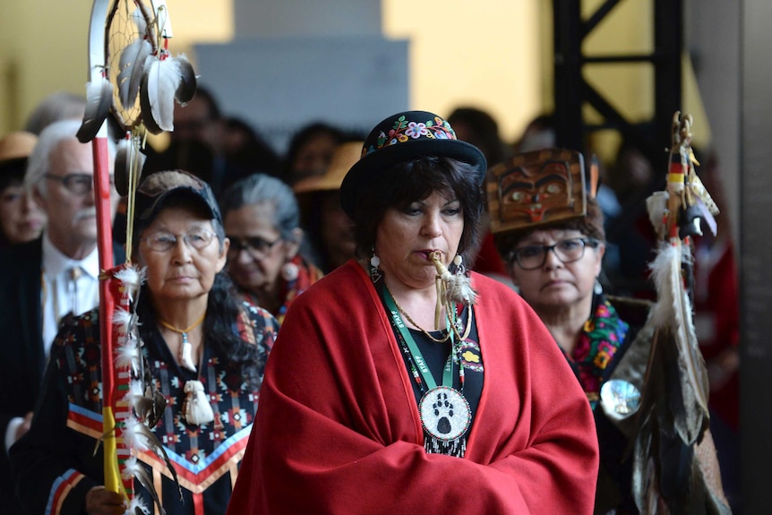 The opening procession shows three Indigenous women in traditional clothing.