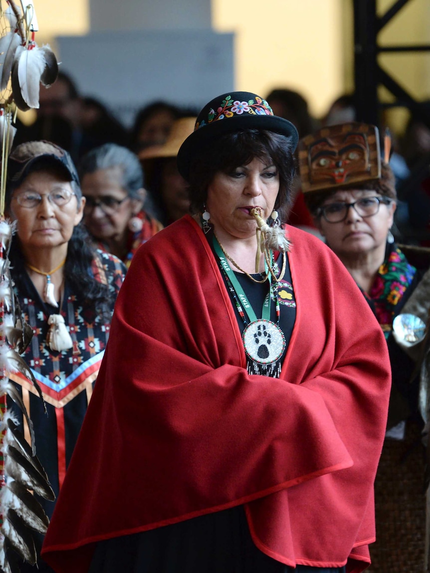The opening procession shows three Indigenous women in traditional clothing.