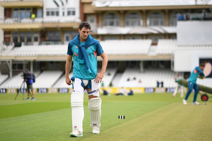 Australian cricket captain Pat Cummins walks beside a green-top pitch at The Oval in the lead-up to a Test match.