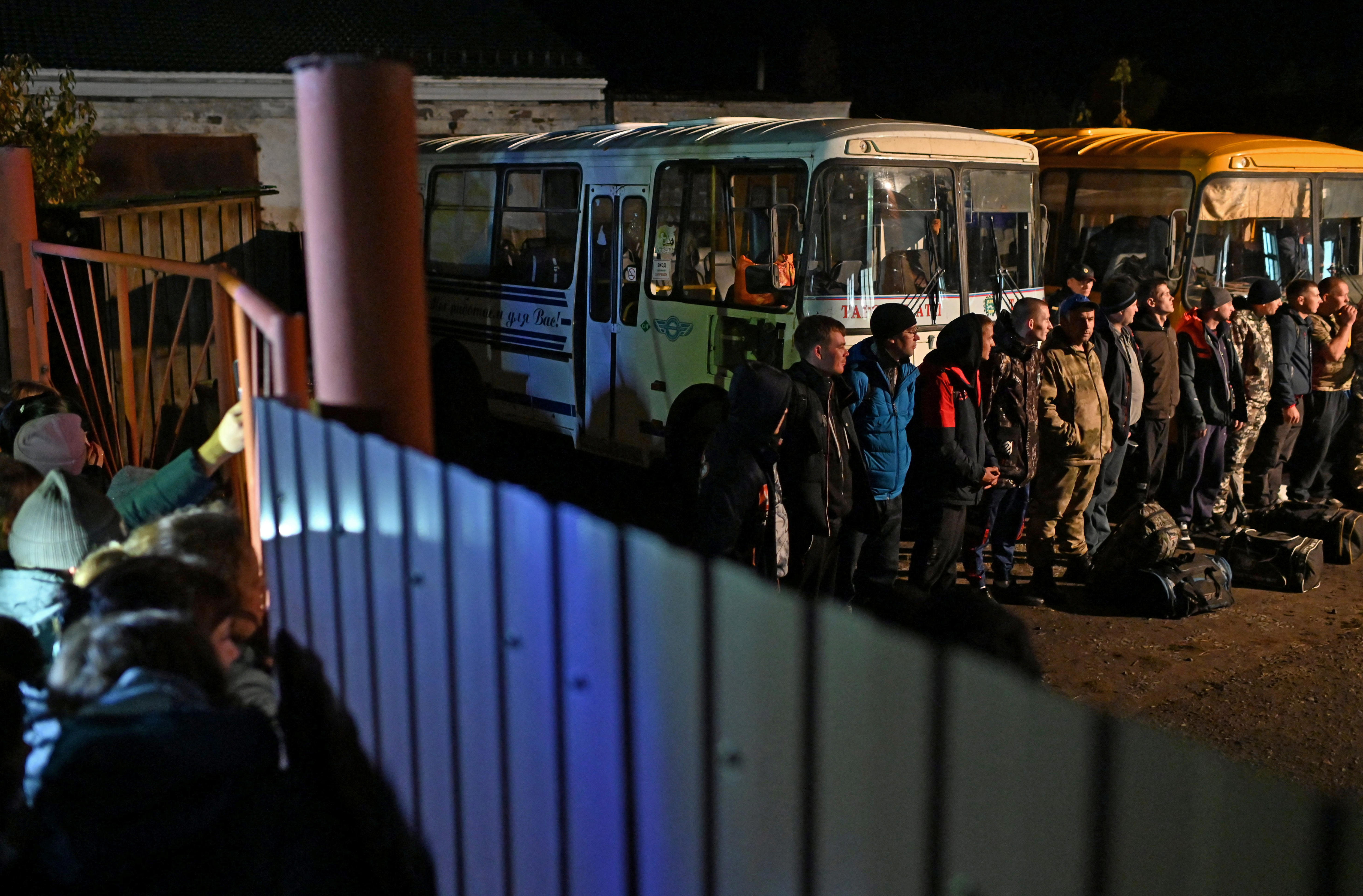 Recently mobilised reservists line up outside a recruitment office in front of busses.