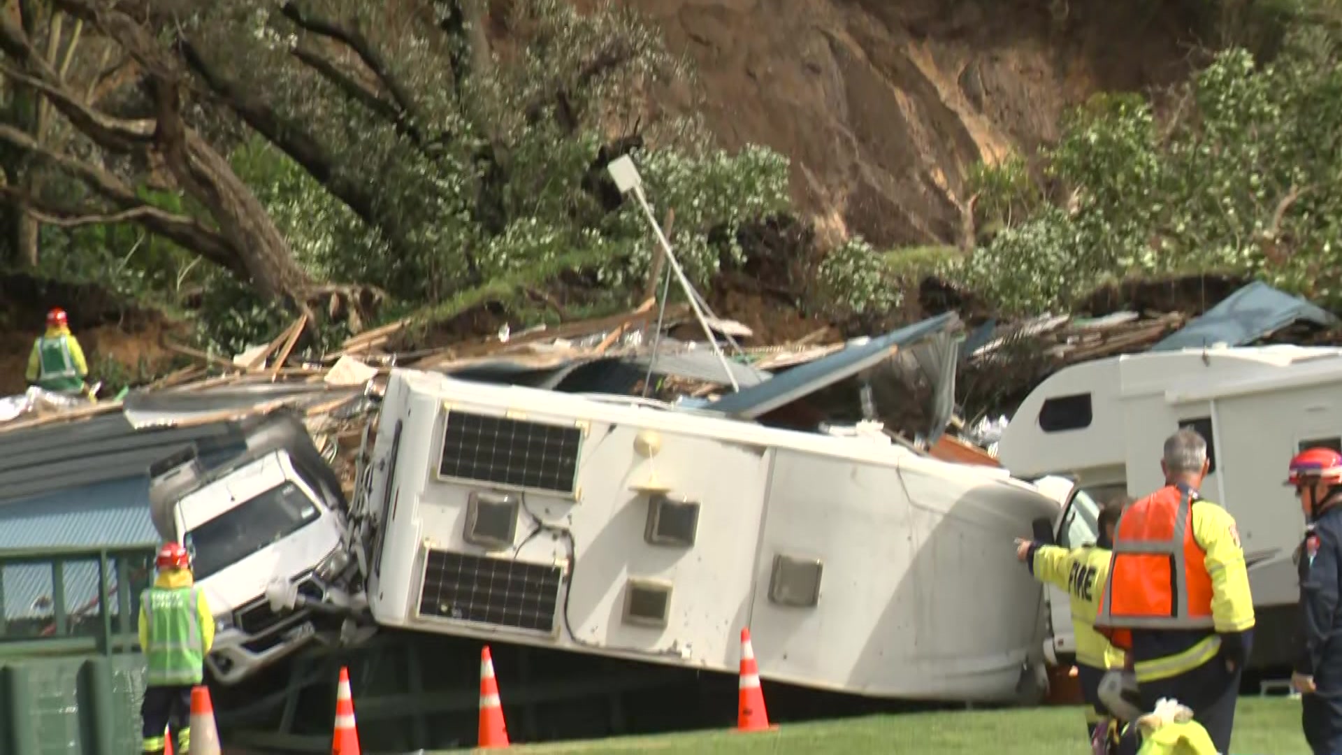Caravans and vehicles on their side with a land slip in the background,