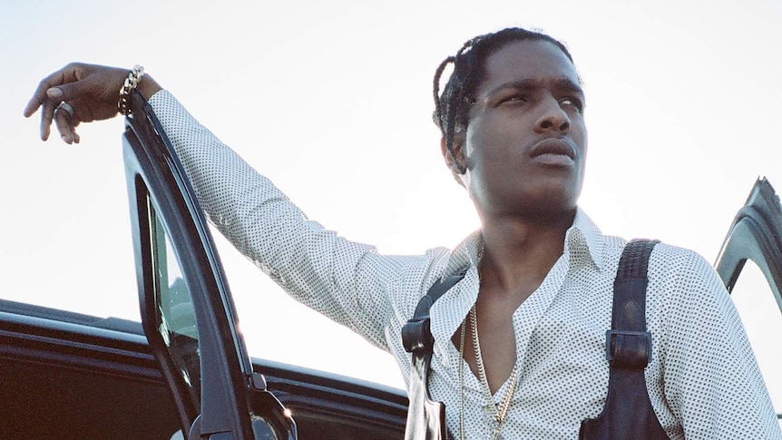 ASAP Rocky leans his arm against a car door and looks out to the distance