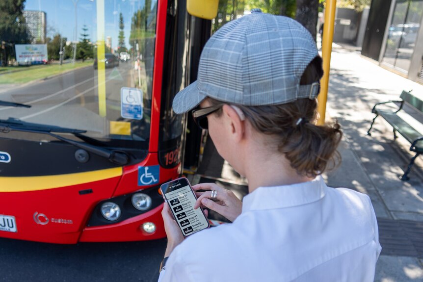 A person using an app near a bus.