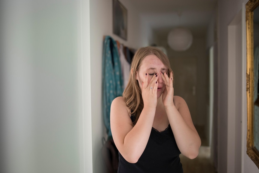 Sofie wipes tears away from her face at home