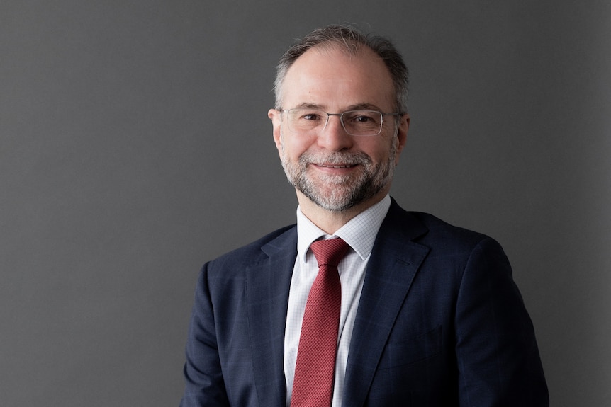 An economist sitting, smiling at camera.