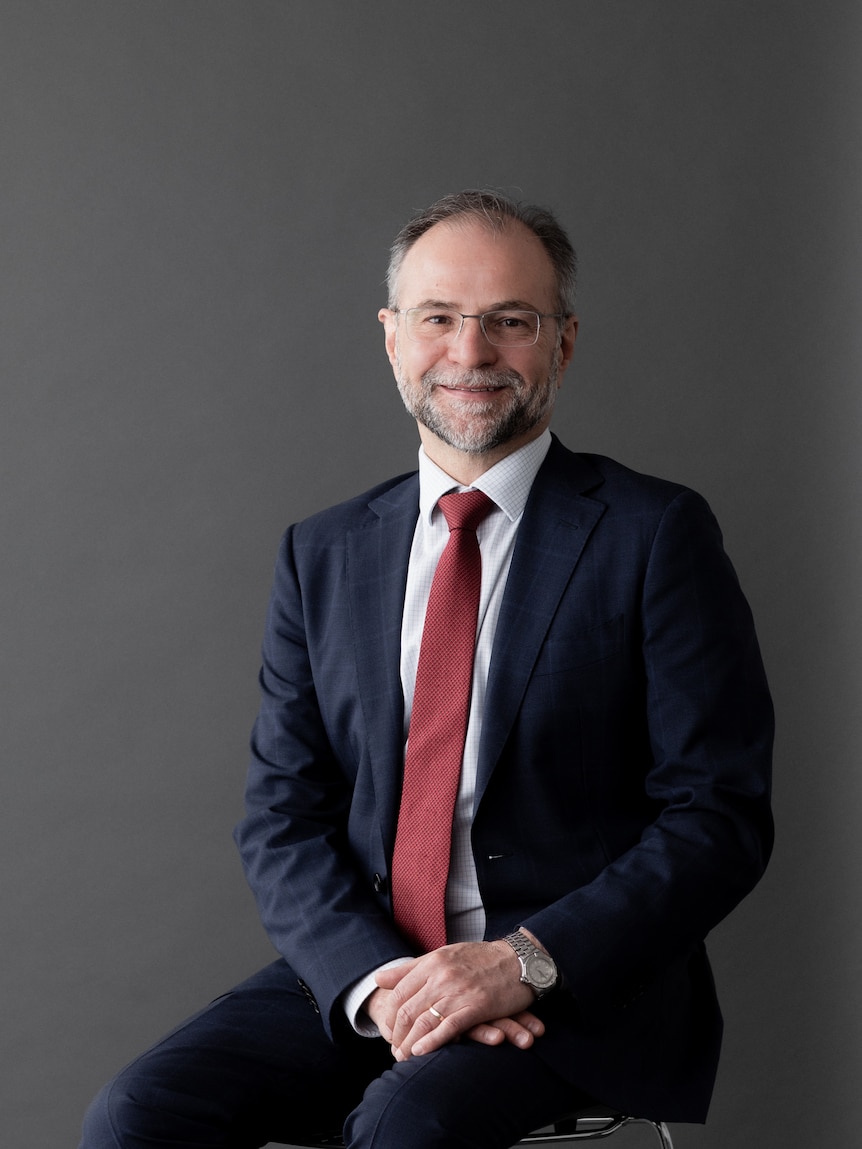 An economist sitting, smiling at camera 