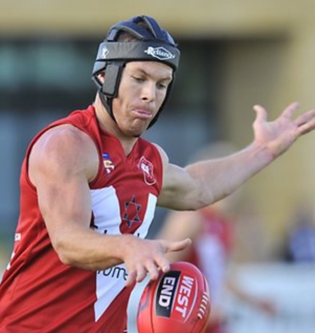 Luke Ivens wearing a helmet is about to kick the football during a game