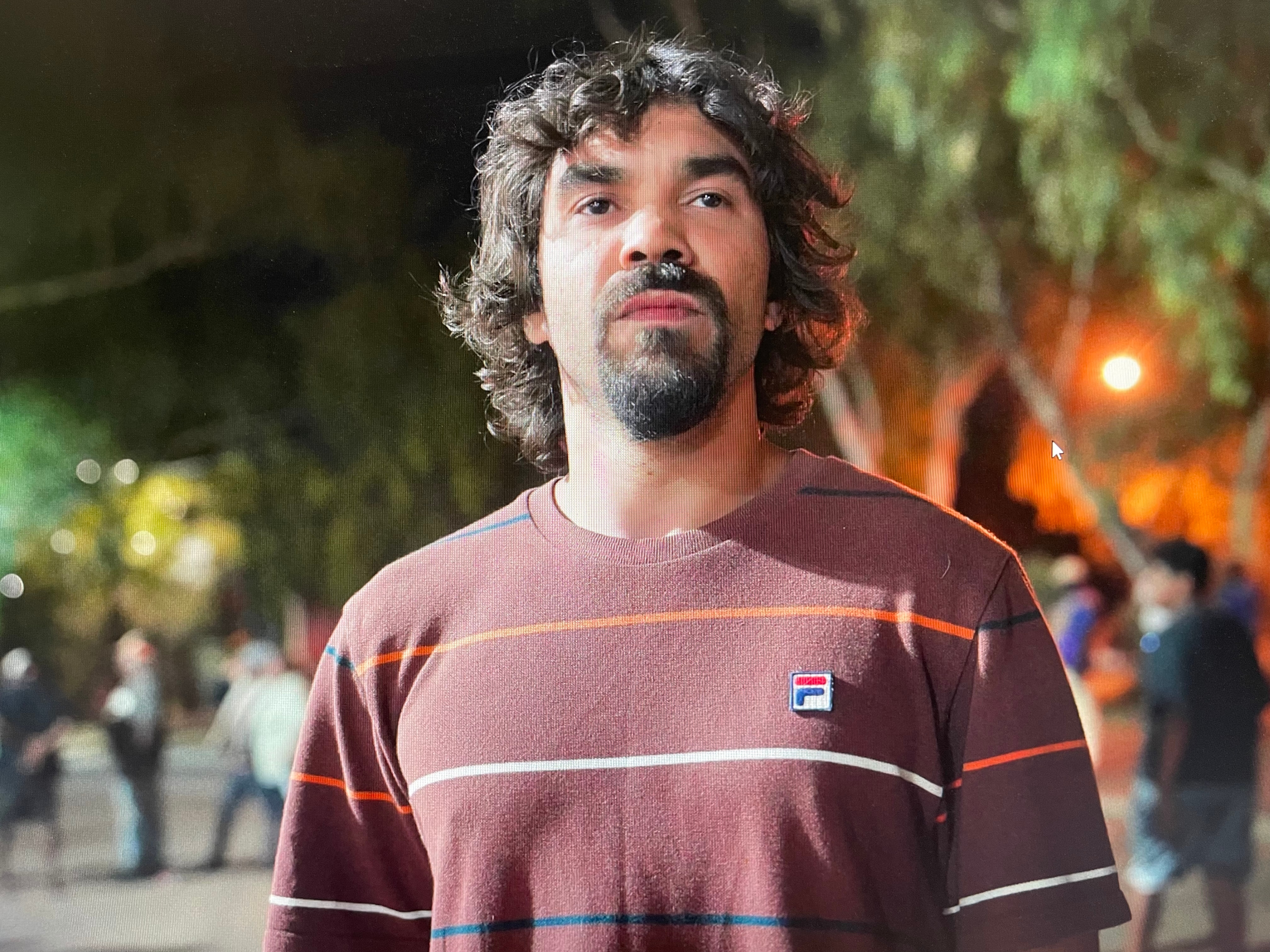 Un hombre vestido con una camiseta se encuentra frente a un grupo de personas.