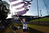 A young Geelong fan holds a large Cats flag at Marrara Oval