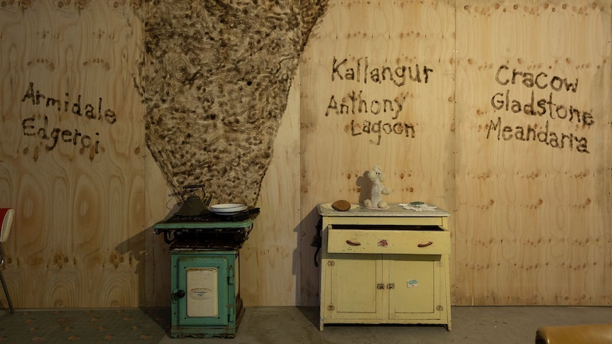 Artistic image of old kitchen furniture - an oven and a small sideboard against a wall with painted words