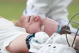 Steve Smith lies on his back with his arms splayed out alongside him as a physio kneels over him