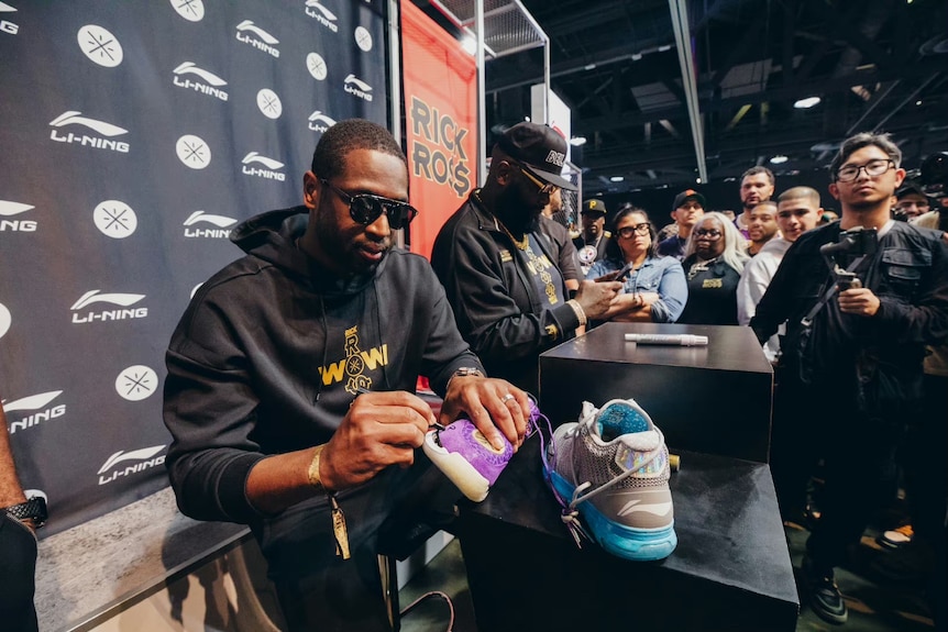 NBA player Dwyane Wade signing a sneaker at a event in China.