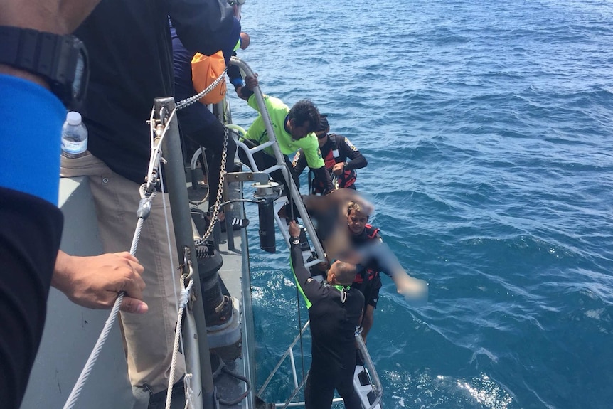 Divers on a rubber raft retrieve a body during a search operation