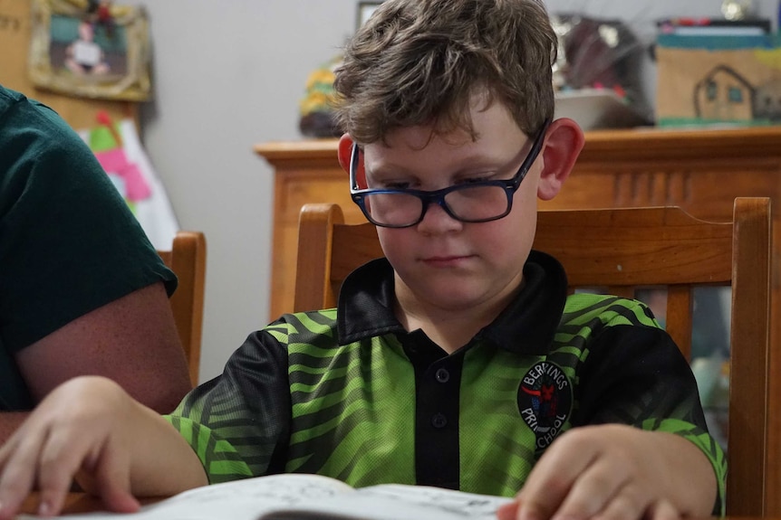 Darwin mum Naomi Hunter sits next to her son Bailey as he reads a book.