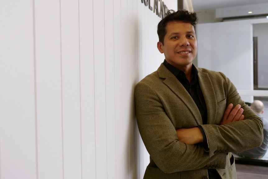 Man folding arms leaning on wall and smiling