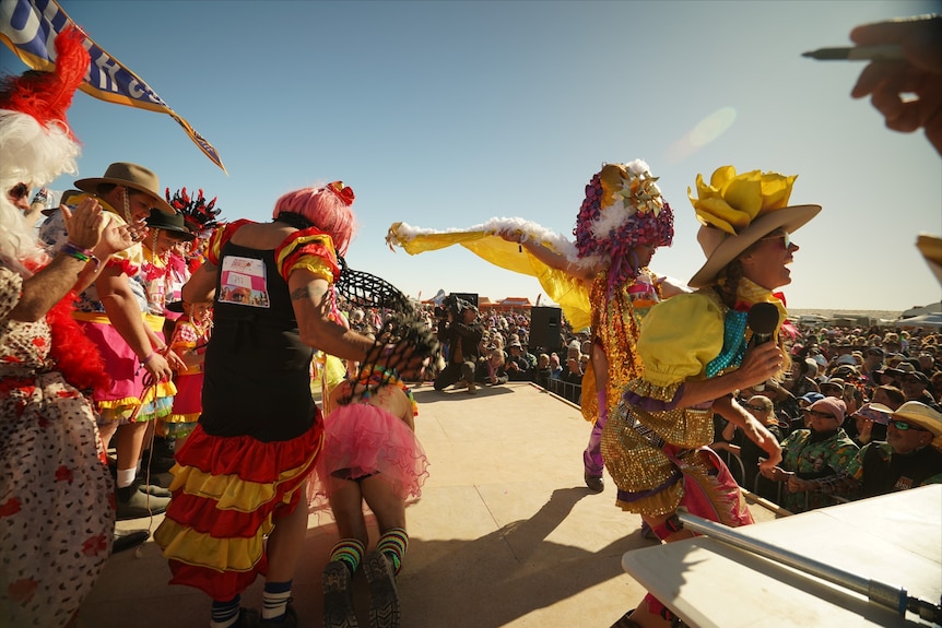 People in bright costumes dancing on a stage.