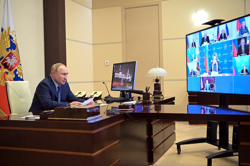 Vladimir Putin hablando desde su escritorio a los miembros del Consejo de Seguridad a través de un enlace de video.
