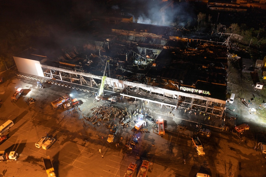 Ukrainian State Emergency Service firefighters work to extinguish a fire at a shopping center burned after a rocket attack.