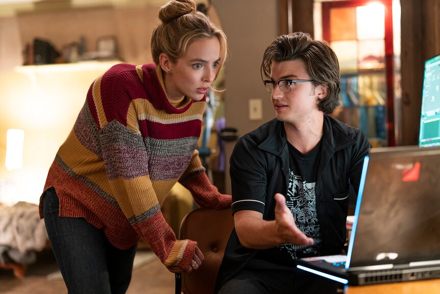 Film still from Free Guy (2021) showing Jodie Comer and Joe Keery discussing information on a laptop screen.