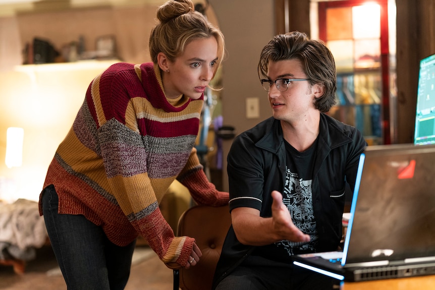 Film still from Free Guy (2021) showing Jodie Comer and Joe Keery discussing information on a laptop screen.
