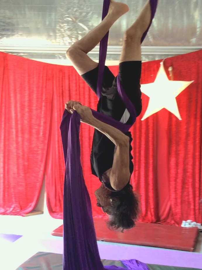 Woman hanging upside down on circus silks