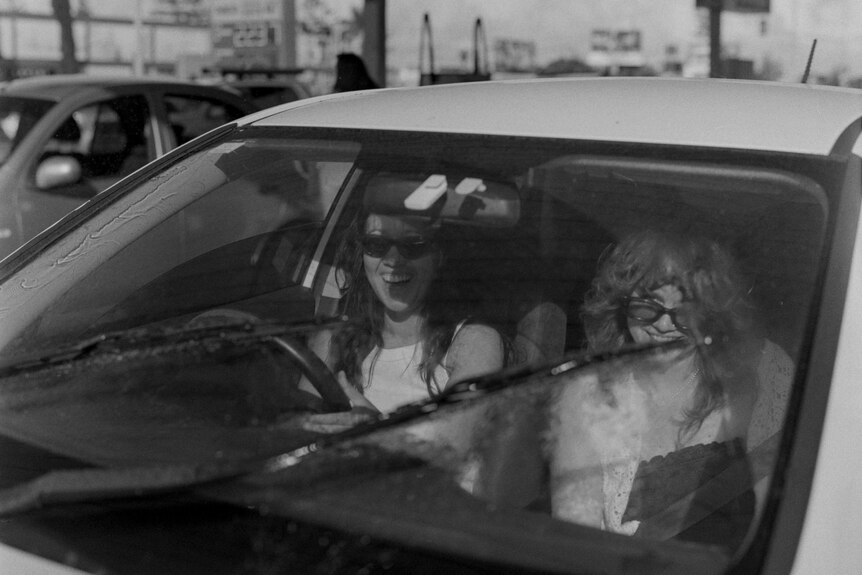 Two girls smiling inside of car 