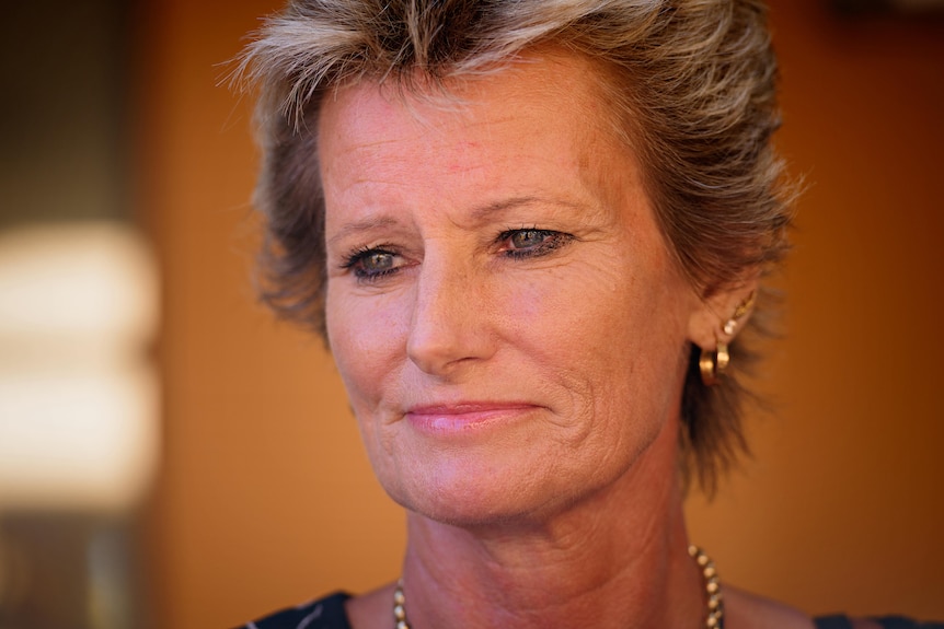 A close-up photo of a woman with short blonde hair and a serious expression. 