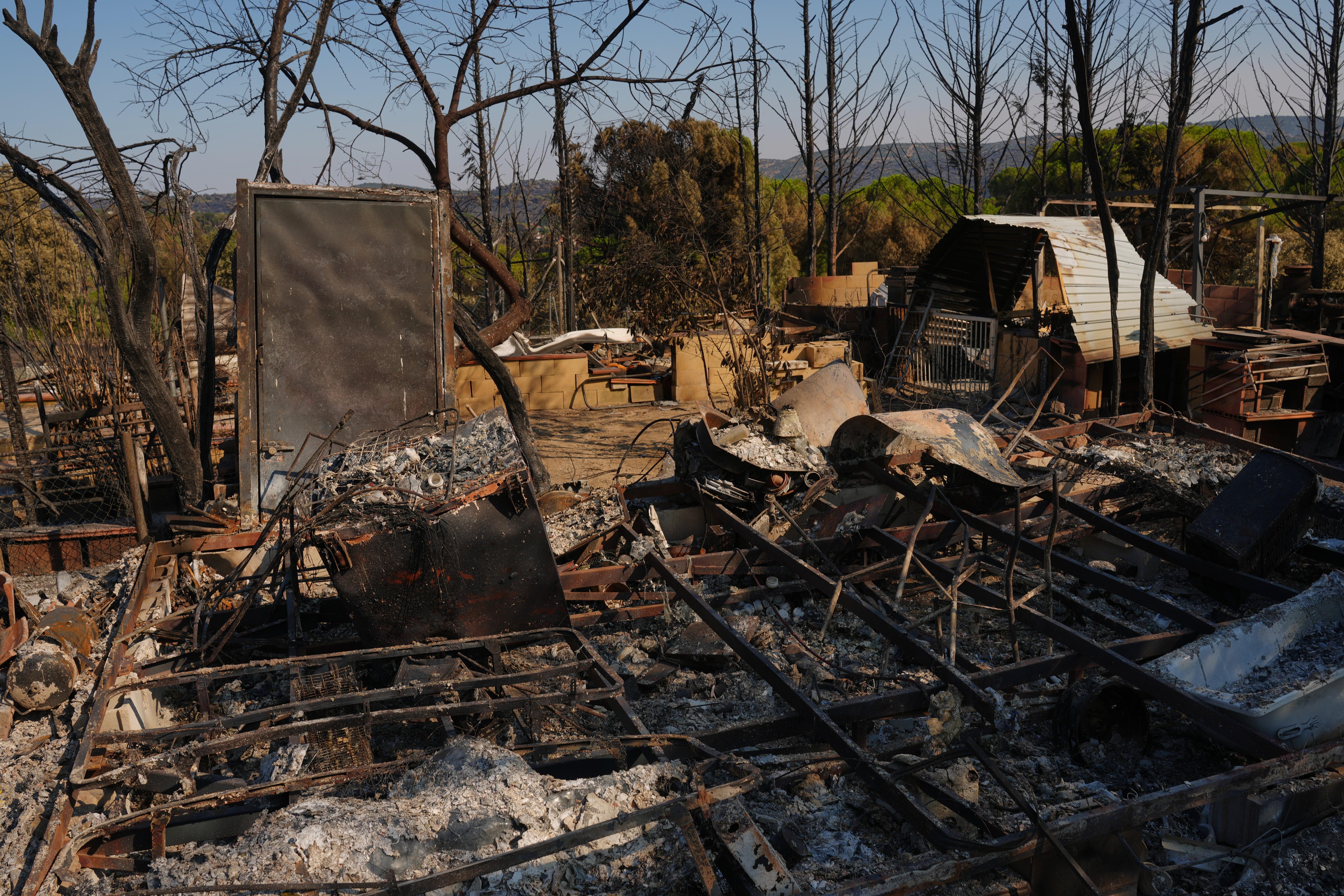 Smoke rises from burnt out houses and trees.