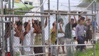 Asylum-seekers look through a fence at the Manus Island detention centre in Papua New Guinea