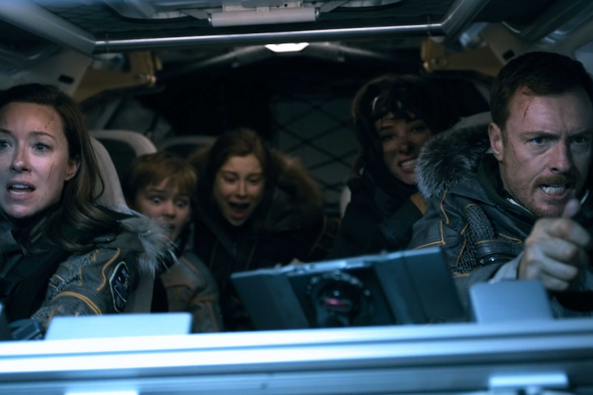 The Robinson family in a space vehicle  with the two children screaming
