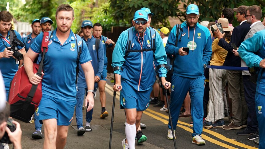 Australia bowler Nathan Lyon arrives on crutches at Lord's before a day of play in an Ashes Test. Fans watch on.