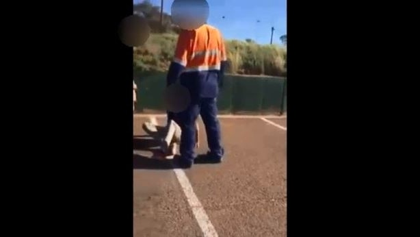 A man stands over a teenager who is sitting on the ground in Port Augusta