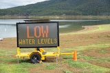 Lake Moogerah with warning sign 'low water levels' on bank, near Boonah in south-west Queensland.