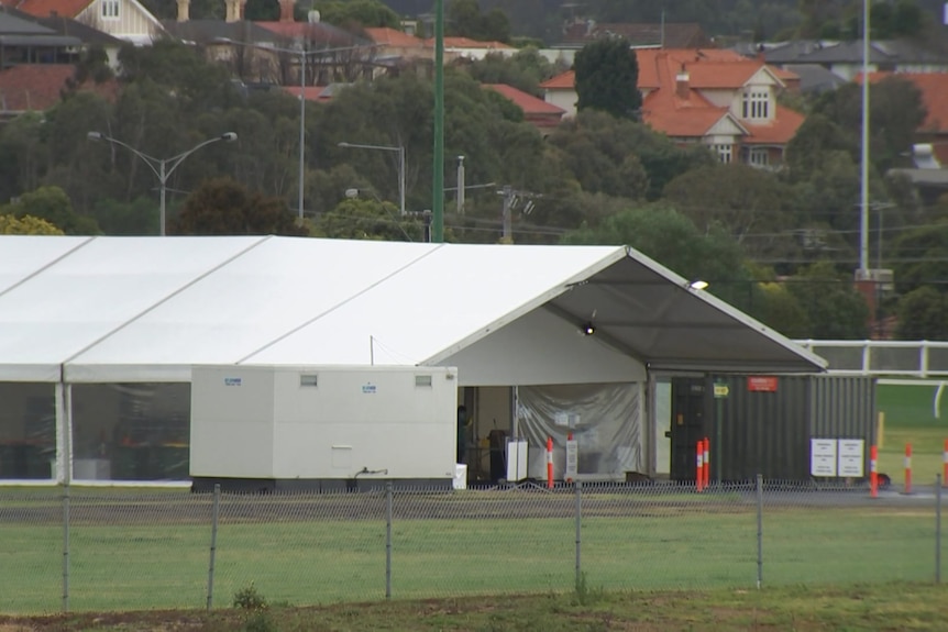 A large white tent for the drive-through testing site lies empty under grey skies.
