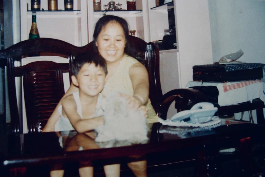 Bang amd his mother were sitting in the sofa chair playing with Duo Duo on the coffee table.