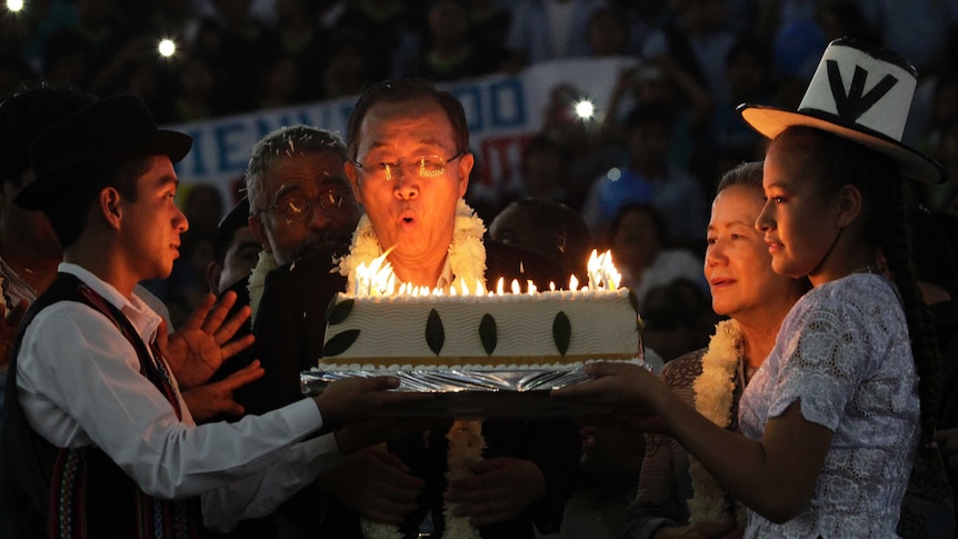 Ban Ki-moon blows out the candles on a cake made of coca leaves