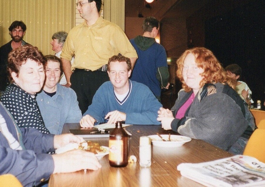 Survivor Richard Tempest sitting with volunteers at the Childers Cultural Centre in June 2000