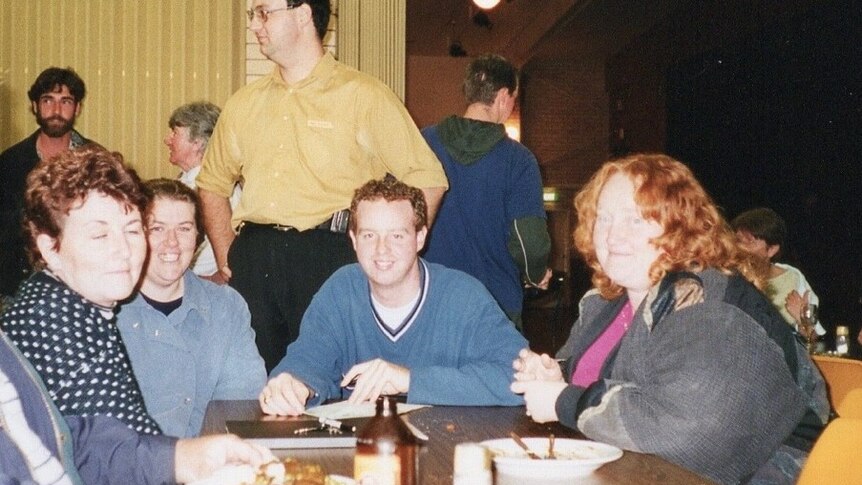 Survivor Richard Tempest sitting with volunteers at the Childers Cultural Centre in June 2000