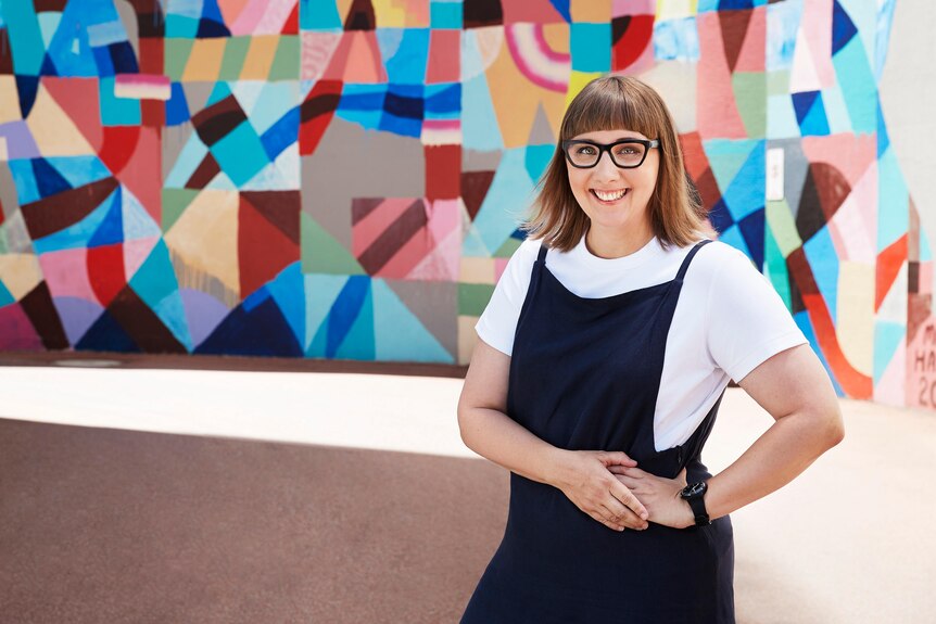 Christine Layton ABC Radio Perth presenter, standing in front of multicoloured mural