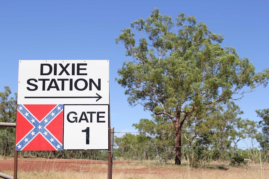 a sign for Dixie Station with a tree in the background
