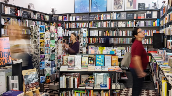 Three female customers looking a book lined shelves.