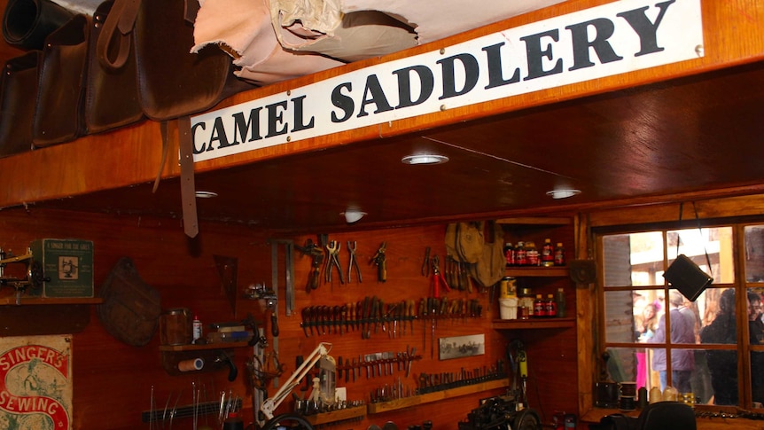 The camel saddlery. A sign on the parapet, a work bench and tools in the background.
