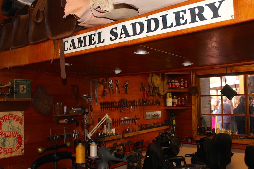 The camel saddlery. A sign on the parapet, a work bench and tools in the background.