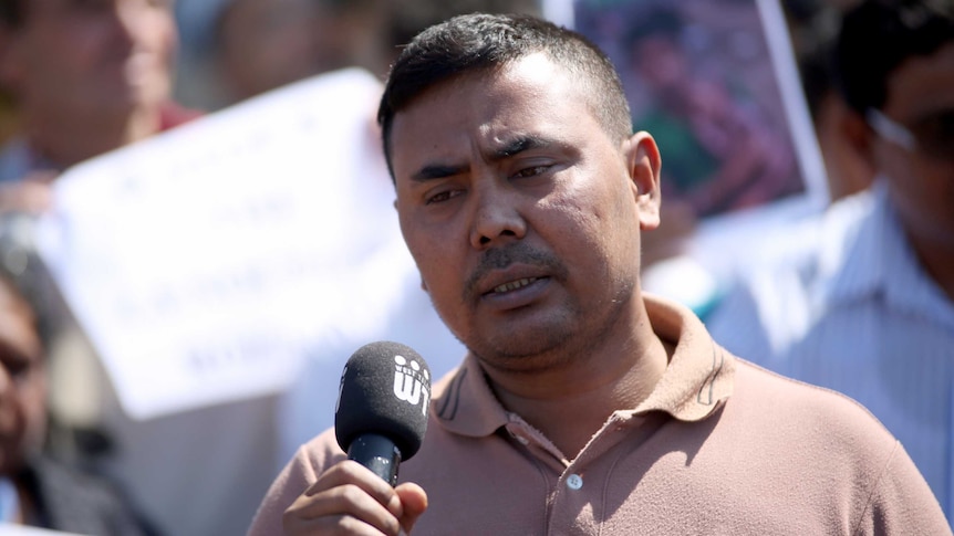 Headshot, man speaking into microphone.